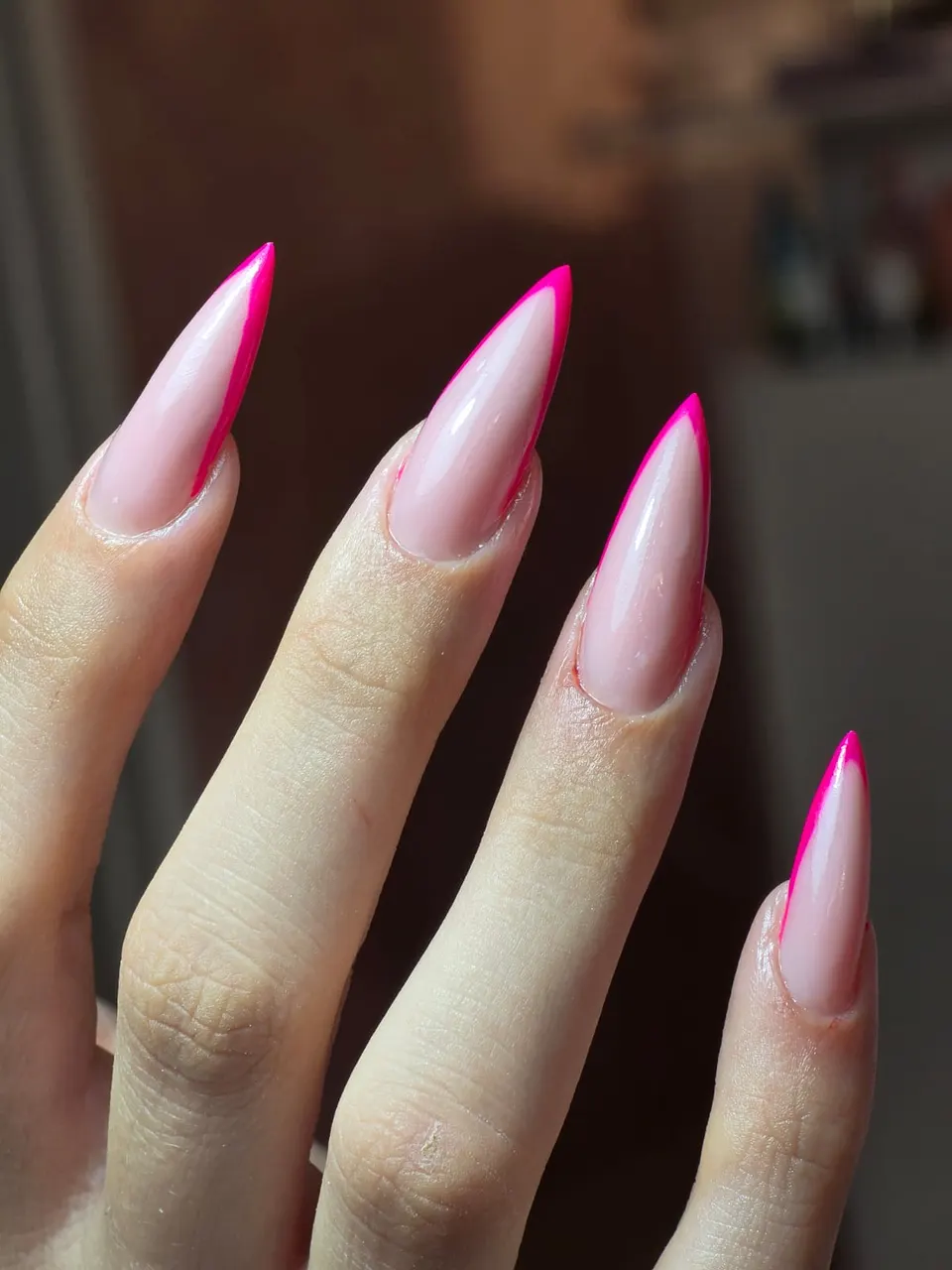 Ružičasti stiletto nokti s fuksija rubom na svijetloj pozadini