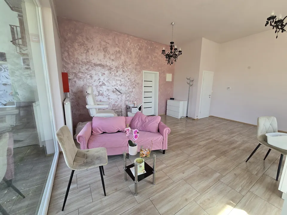 Interijer salona LAROSE s ružičastom sofom, ružičastim zidom i lusterom
